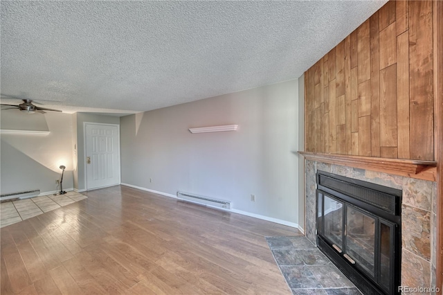 unfurnished living room featuring a baseboard heating unit, a glass covered fireplace, wood finished floors, ceiling fan, and a textured ceiling