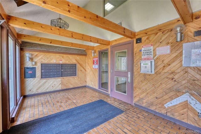 unfurnished sunroom with mail area and beamed ceiling