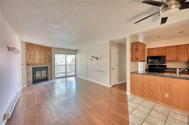 kitchen featuring black appliances, a baseboard heating unit, brown cabinets, ceiling fan, and dark countertops