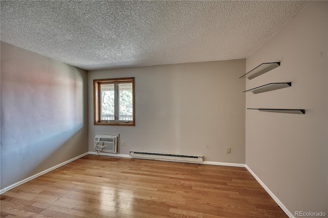 spare room featuring a baseboard radiator, a wall mounted AC, wood-type flooring, a textured ceiling, and baseboards