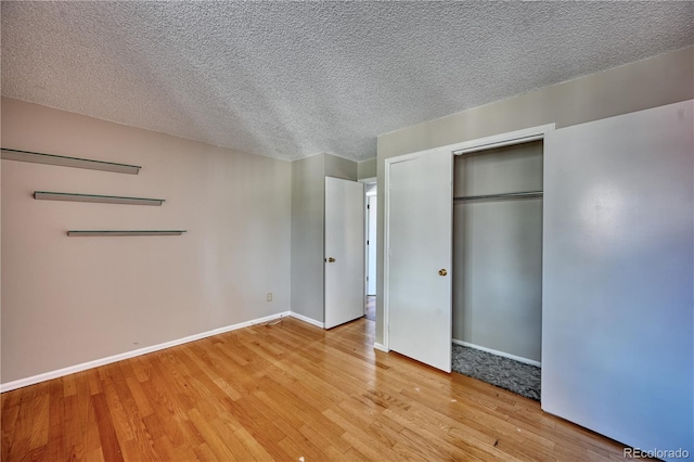 unfurnished bedroom with baseboards, light wood-style floors, a closet, and a textured ceiling