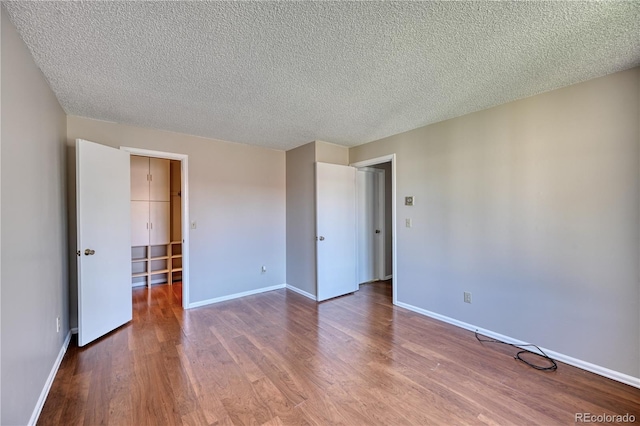 unfurnished bedroom with wood finished floors, a textured ceiling, and baseboards