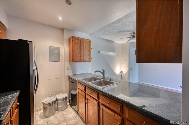 kitchen featuring freestanding refrigerator, a sink, a ceiling fan, brown cabinetry, and electric panel