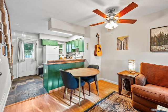 kitchen with white refrigerator, green cabinetry, hardwood / wood-style flooring, ceiling fan, and kitchen peninsula