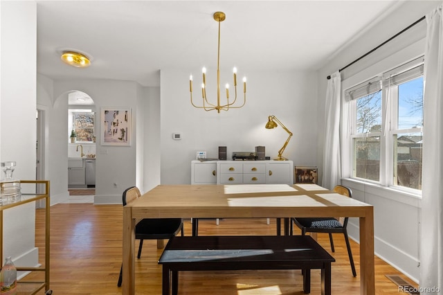 dining room featuring sink, a notable chandelier, and light hardwood / wood-style flooring