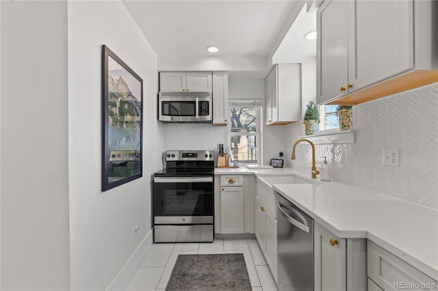 kitchen with sink, backsplash, stainless steel appliances, and light tile patterned flooring