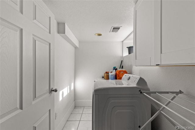 clothes washing area featuring cabinets, washing machine and dryer, and a textured ceiling