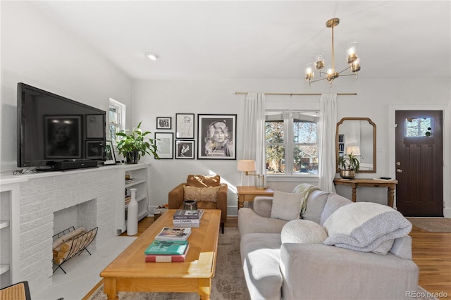 living room with a brick fireplace, a notable chandelier, and light hardwood / wood-style floors