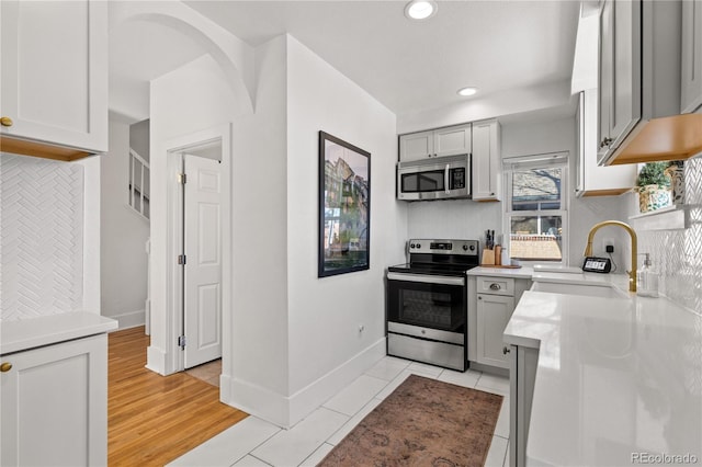 kitchen featuring gray cabinetry, sink, tasteful backsplash, and stainless steel appliances