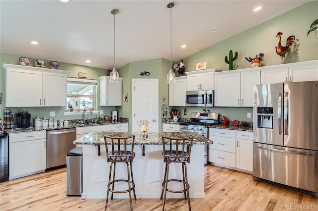 kitchen with dark stone countertops, white cabinetry, stainless steel appliances, and decorative light fixtures