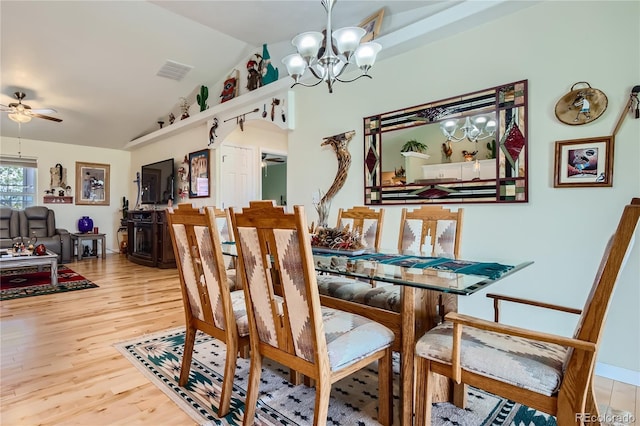 dining space with ceiling fan with notable chandelier, hardwood / wood-style flooring, and lofted ceiling