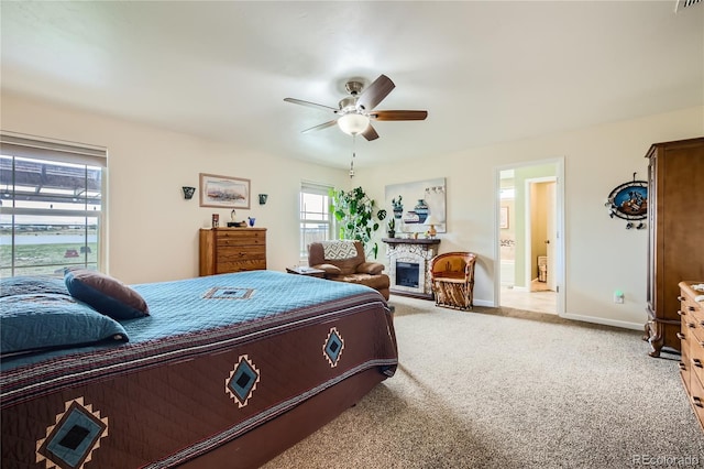 carpeted bedroom with a fireplace, ensuite bath, and ceiling fan