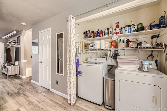 clothes washing area with washer and dryer, a textured ceiling, and light hardwood / wood-style floors