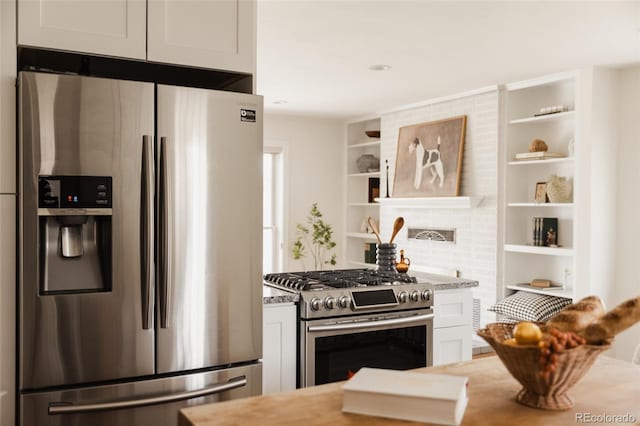 kitchen with light stone counters, open shelves, stainless steel appliances, and white cabinetry