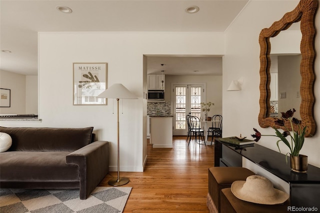 living room featuring recessed lighting, baseboards, ornamental molding, and light wood-style floors