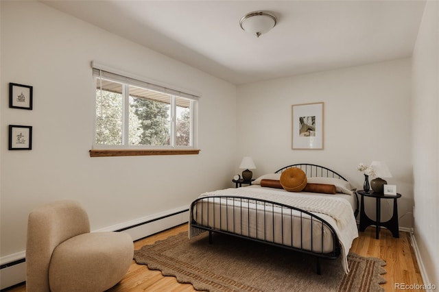 bedroom with baseboards, a baseboard radiator, a baseboard heating unit, and wood finished floors