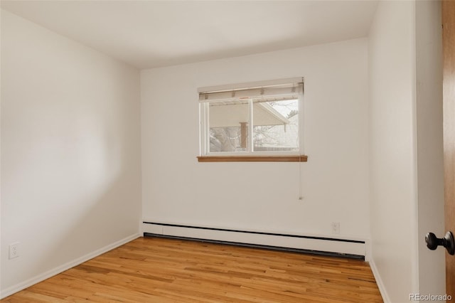 empty room with light wood-type flooring, baseboards, and a baseboard heating unit