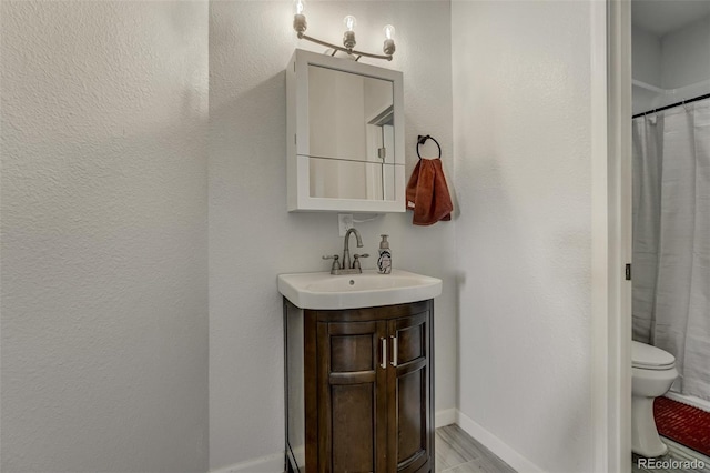 bathroom featuring toilet, vanity, and walk in shower