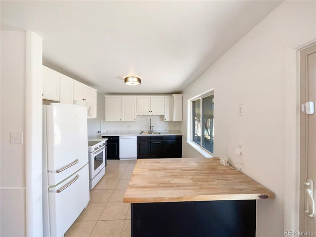 kitchen featuring white appliances, white cabinets, a peninsula, a sink, and light tile patterned flooring