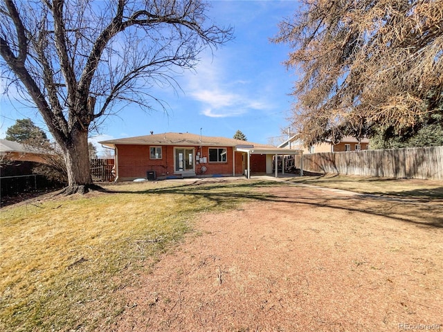 rear view of house with brick siding, a lawn, and a fenced backyard