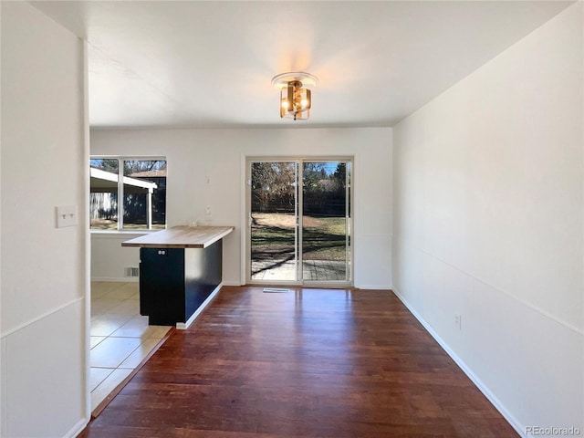 unfurnished dining area with visible vents, baseboards, and wood finished floors