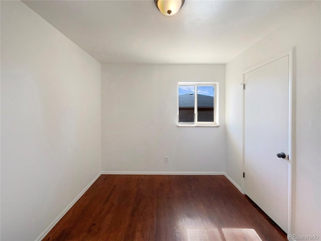 spare room with baseboards and wood finished floors