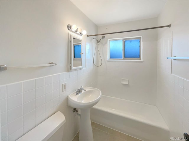 bathroom featuring toilet, shower / bathtub combination, tile patterned flooring, and tile walls