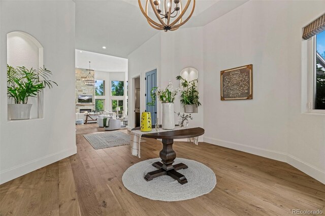 entrance foyer with a towering ceiling, a chandelier, and light wood-type flooring