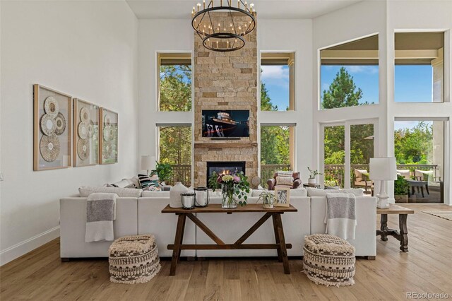 living room featuring a fireplace, an inviting chandelier, light hardwood / wood-style floors, and a high ceiling