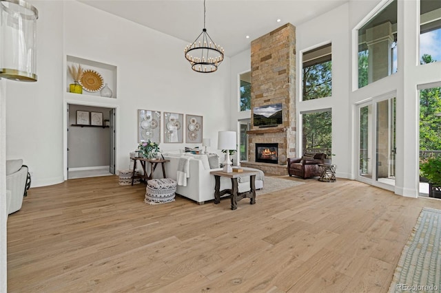 living room featuring a towering ceiling, light hardwood / wood-style floors, and a healthy amount of sunlight