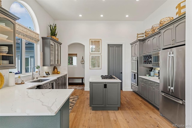 kitchen featuring stainless steel appliances, light hardwood / wood-style floors, a wealth of natural light, a center island, and gray cabinets