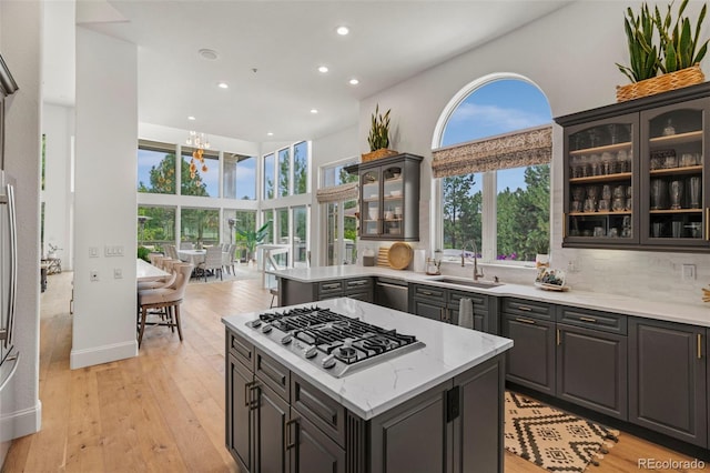 kitchen featuring backsplash, sink, a center island, appliances with stainless steel finishes, and light hardwood / wood-style floors