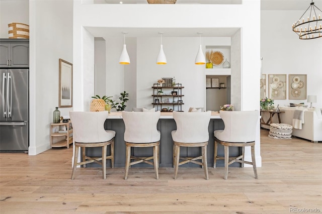 kitchen with stainless steel refrigerator, light hardwood / wood-style floors, pendant lighting, and gray cabinets