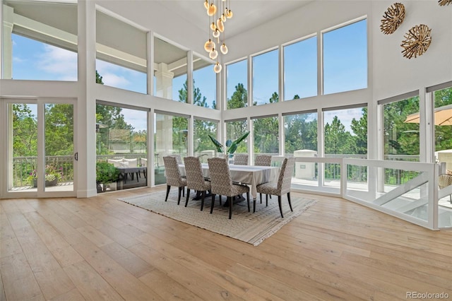 interior space with a towering ceiling, light hardwood / wood-style floors, and a chandelier