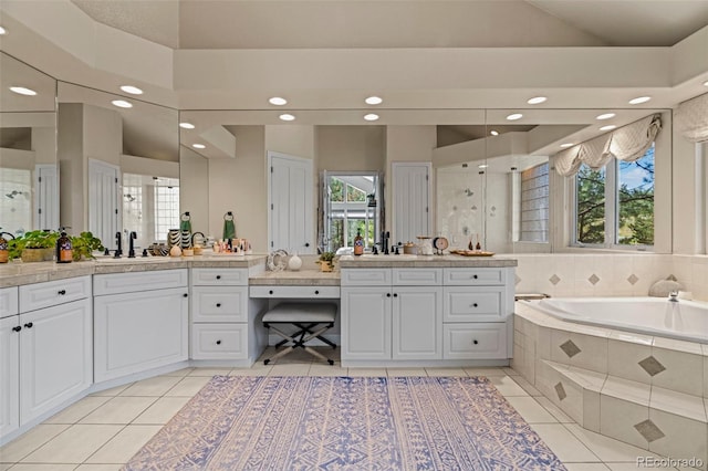 bathroom with a wealth of natural light, independent shower and bath, tile patterned floors, and vanity