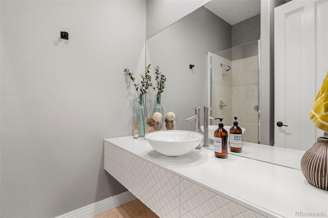 bathroom with hardwood / wood-style flooring, a tile shower, and vanity