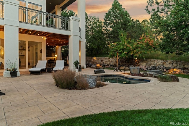 pool at dusk with a jacuzzi and a patio area