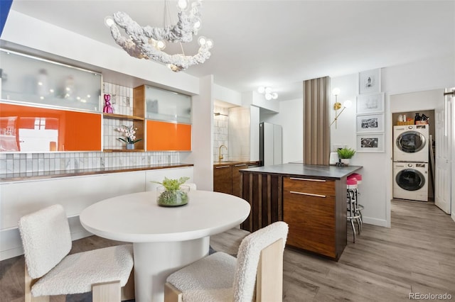 790 N Washington St Unit 407, Denver, CO 80203 - dining room with stacked washer / drying machine, light wood finished floors, and a chandelier