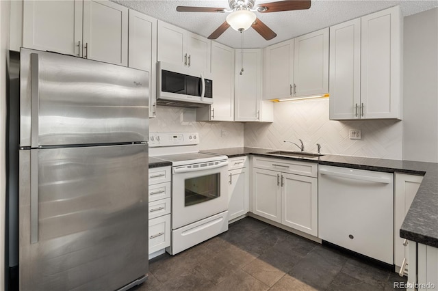 kitchen featuring ceiling fan, a sink, white appliances, white cabinetry, and decorative backsplash