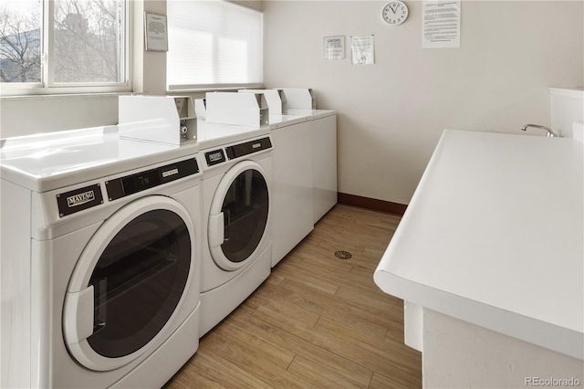 common laundry area featuring washing machine and clothes dryer, baseboards, and light wood-style floors