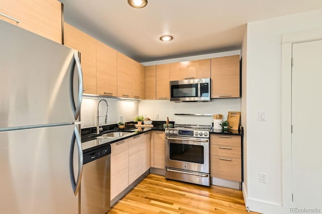 2837 Vallejo St Unit 102, Denver, CO 80211 - kitchen with appliances with stainless steel finishes, dark countertops, light brown cabinets, light wood finished floors, and recessed lighting