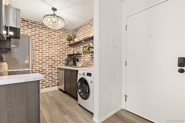 laundry area with a sink, washer / clothes dryer, a textured ceiling, light wood-style floors, and laundry area