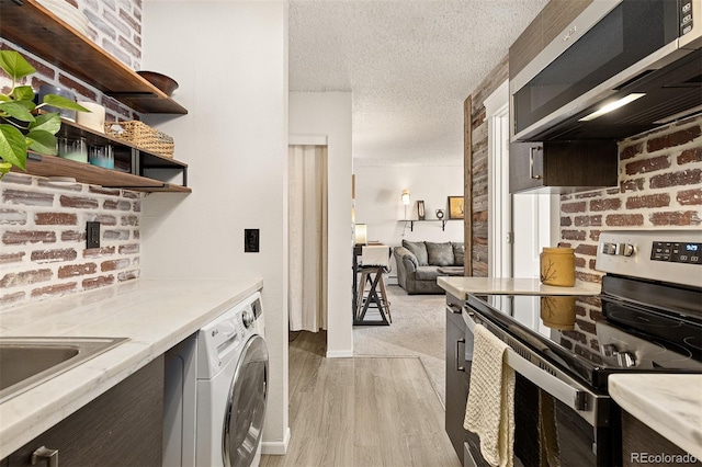 kitchen featuring washer / dryer, sink, stainless steel appliances, a textured ceiling, and light wood-type flooring