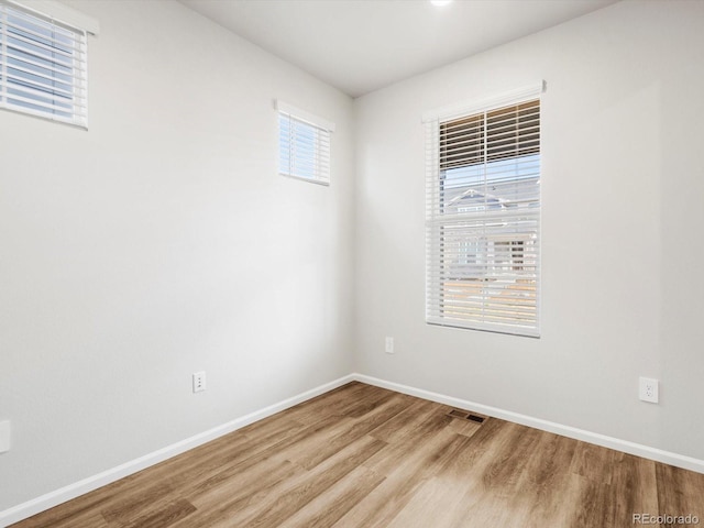 spare room with baseboards, wood finished floors, and visible vents