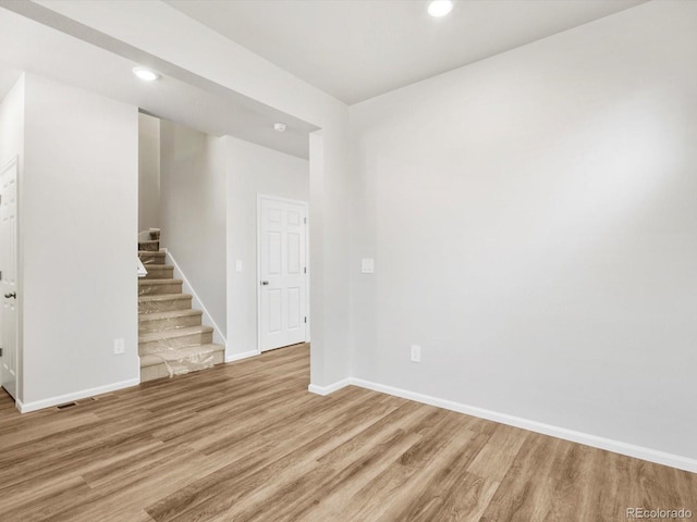 spare room with visible vents, stairs, wood finished floors, baseboards, and recessed lighting