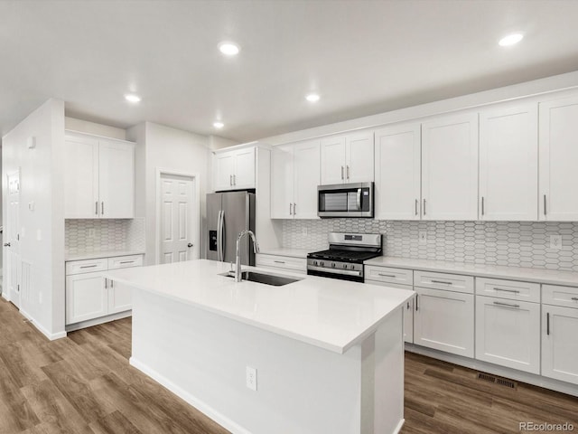 kitchen with appliances with stainless steel finishes, tasteful backsplash, a sink, dark wood-type flooring, and visible vents