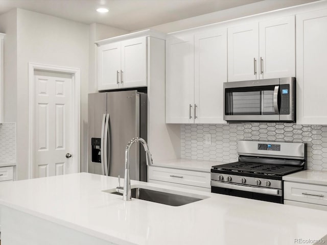 kitchen with light countertops, white cabinets, appliances with stainless steel finishes, and a sink