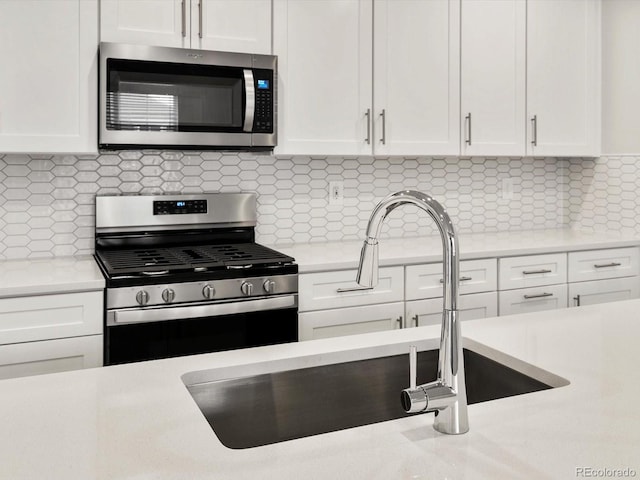 kitchen with light countertops, backsplash, stainless steel appliances, and white cabinetry