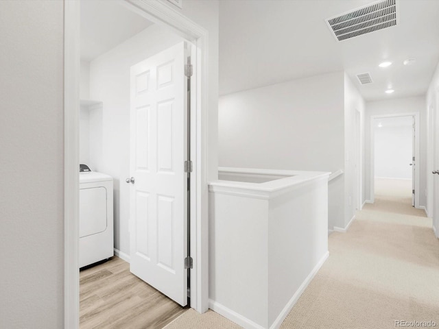 hallway with baseboards, washer / dryer, and visible vents