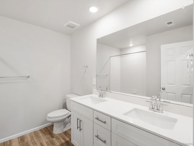 bathroom featuring a sink, toilet, wood finished floors, and visible vents